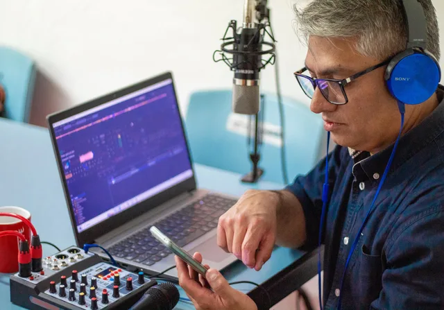 A man using audio equipment and a laptop while recording a podcast with headphones and microphone. Budgeting for production and talent costs: quote lines