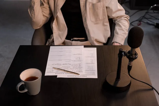 A podcast setup with microphone, papers, and coffee cup on a desk. Comparing baked-in ads with dynamic insertion
