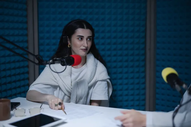 A woman in a podcast studio with microphones and headphones, focused on a discussion. Podcast ad placement and format