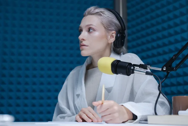 Confident woman wearing headphones hosting a podcast in a soundproof studio. Writing podcast ad scripts